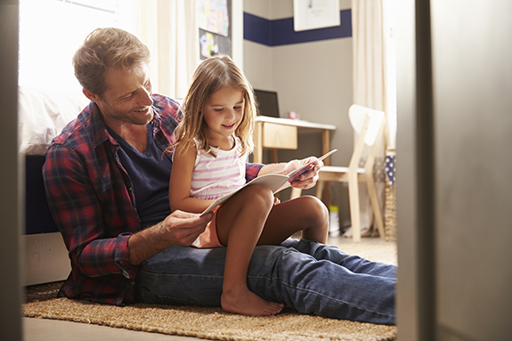 Father and daughter reading a PJ Library book together.