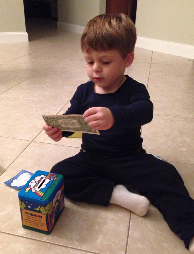 Child putting money in tzedakah box