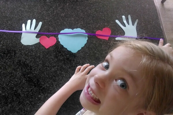 A child making a hug greeting card out of craft papers.